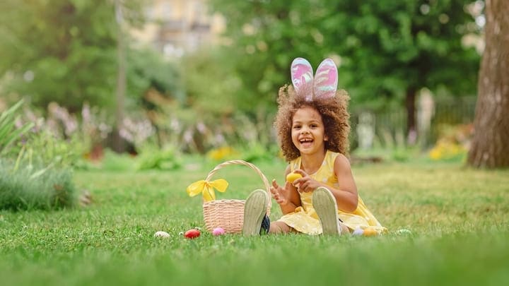 Child wearing bunny ears on an Easter egg hunt in the park