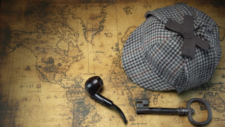 Sherlock Holmes's deerstalker hat and pipe on top of an old world map